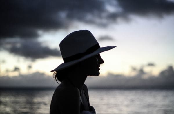 Young woman with a wide-brimmed hat in an outdoor setting.